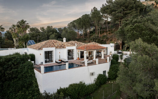 El Madroñal Villa in Benahavís with traditional Spanish cortijo design, white lime-clad walls, and red-tiled roofs, surrounded by lush greenery.