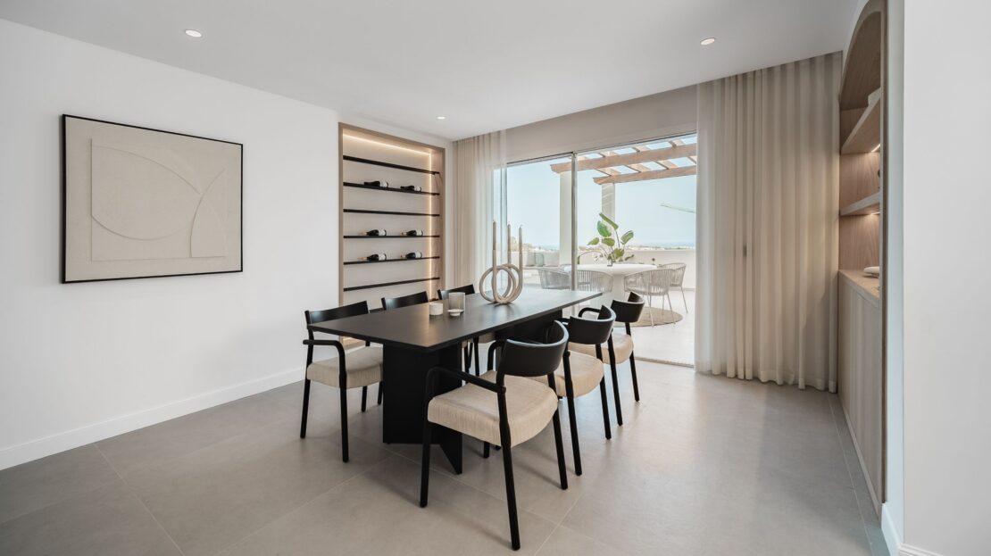Wider perspective of six-seater dining table with wall-embedded wine cellar and LED lighting in Los Belvederes penthouse, Marbella luxury interior