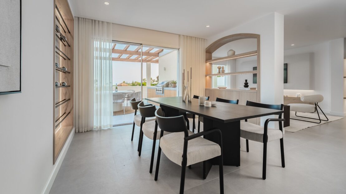 Modern dining table for six with space-efficient wall wine cellar and LED lighting in Los Belvederes penthouse, Marbella luxury home