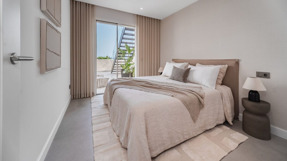 Modern guest bedroom under glass-railed staircase with sliding doors to terrace in Los Belvederes penthouse, Marbella