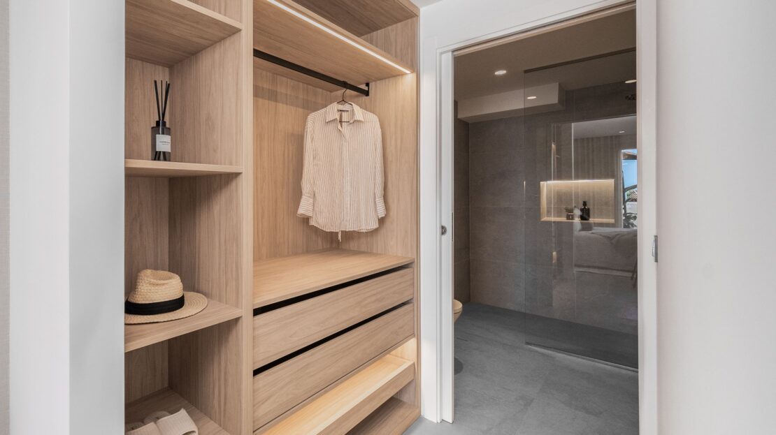 Elegant walk-in wardrobe with premium hangers and organizational sections outside bathroom in Los Belvederes penthouse, Marbella