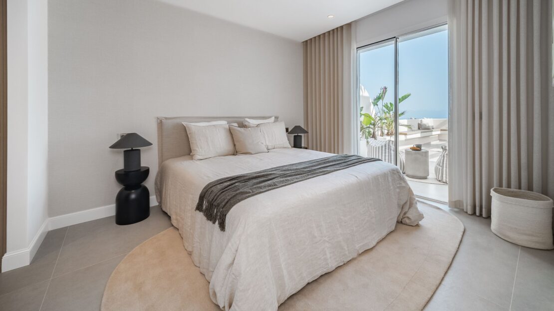 Luxury king bedroom featuring upholstered headboard wall and glass doors to terrace in Los Belvederes penthouse, Marbella