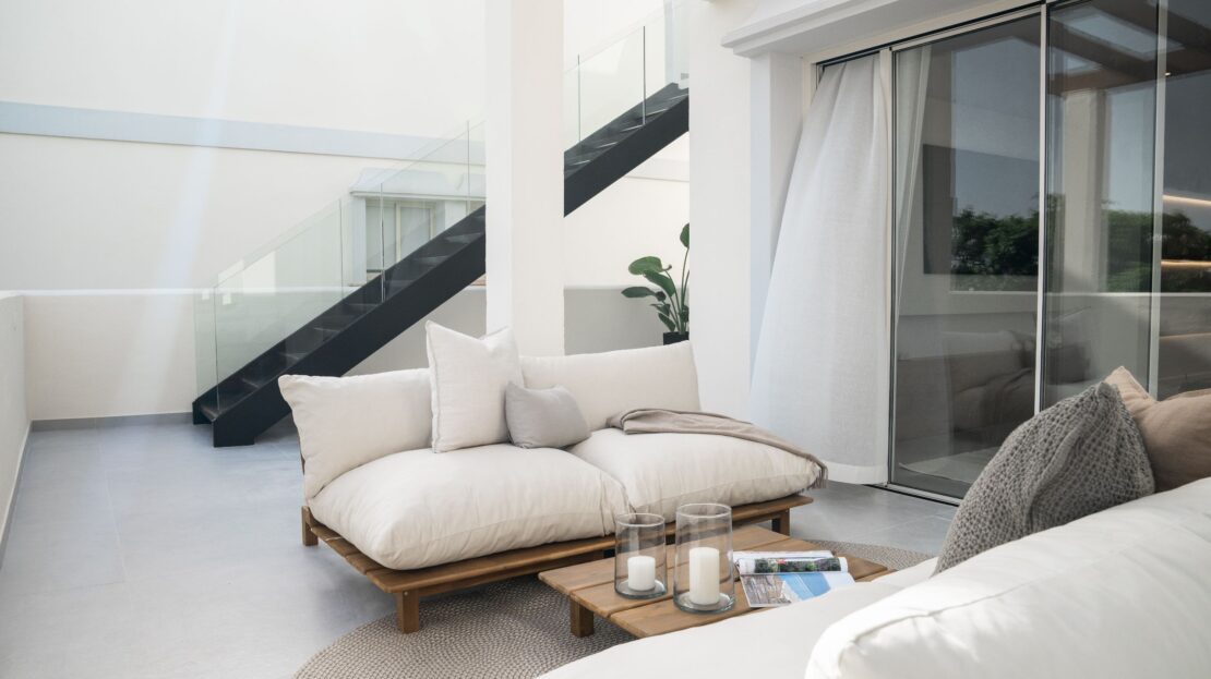 Modern lounge seating with side table beside glass sliding doors in Los Belvederes penthouse rooftop, Marbella luxury residence
