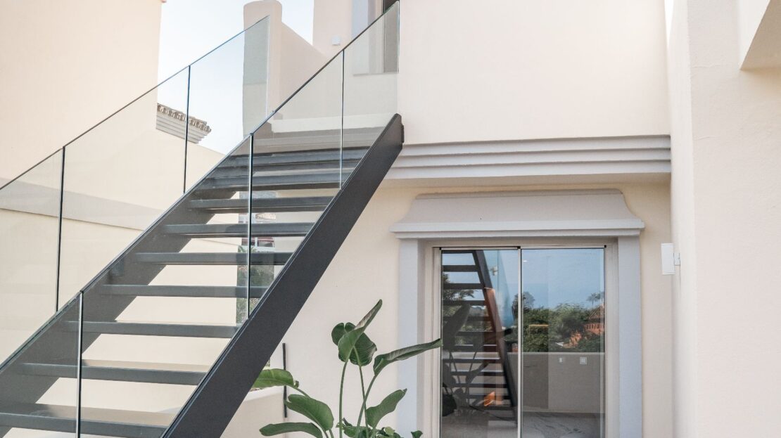 Modern glass-railed staircase ascending to a room, in Los Belvederes luxury penthouse, Marbella