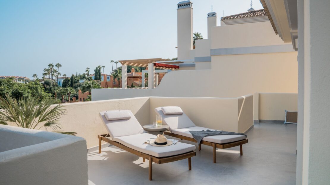Alternate view of luxury sunbeds on Los Belvederes penthouse rooftop terrace showcasing Marbella's coastline and mountain vistas from behind