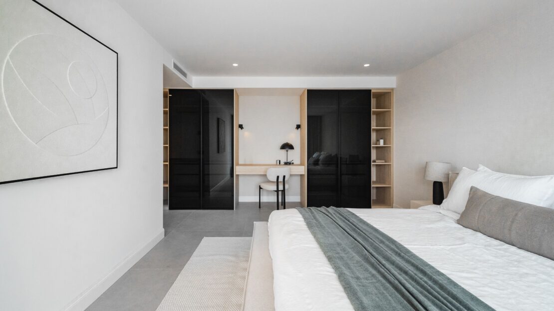 Spacious master bedroom featuring king bed and built-in study area with mirrored wardrobes in Los Belvederes luxury penthouse, Marbella