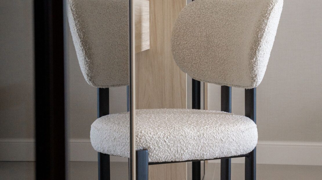 Designer accent chair positioned opposite full-length mirrored wardrobes in Los Belvederes penthouse dressing area, Marbella luxury residence