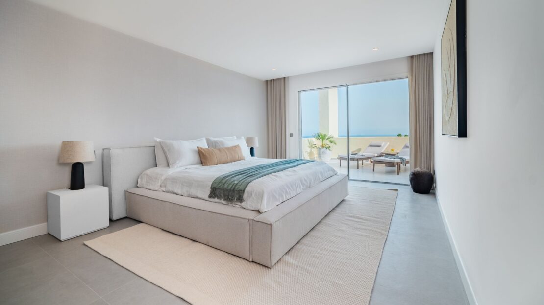 Luxury king-sized bedroom with designer bedside lamps, floor-to-ceiling windows, and balcony access in Los Belvederes penthouse, Marbella